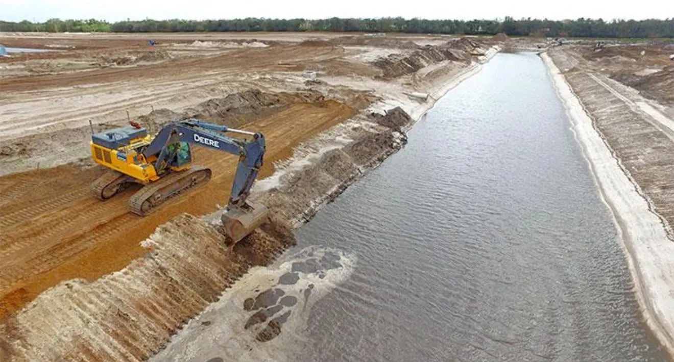 Escavadeira hidráulica escavando canal de drenagem com água