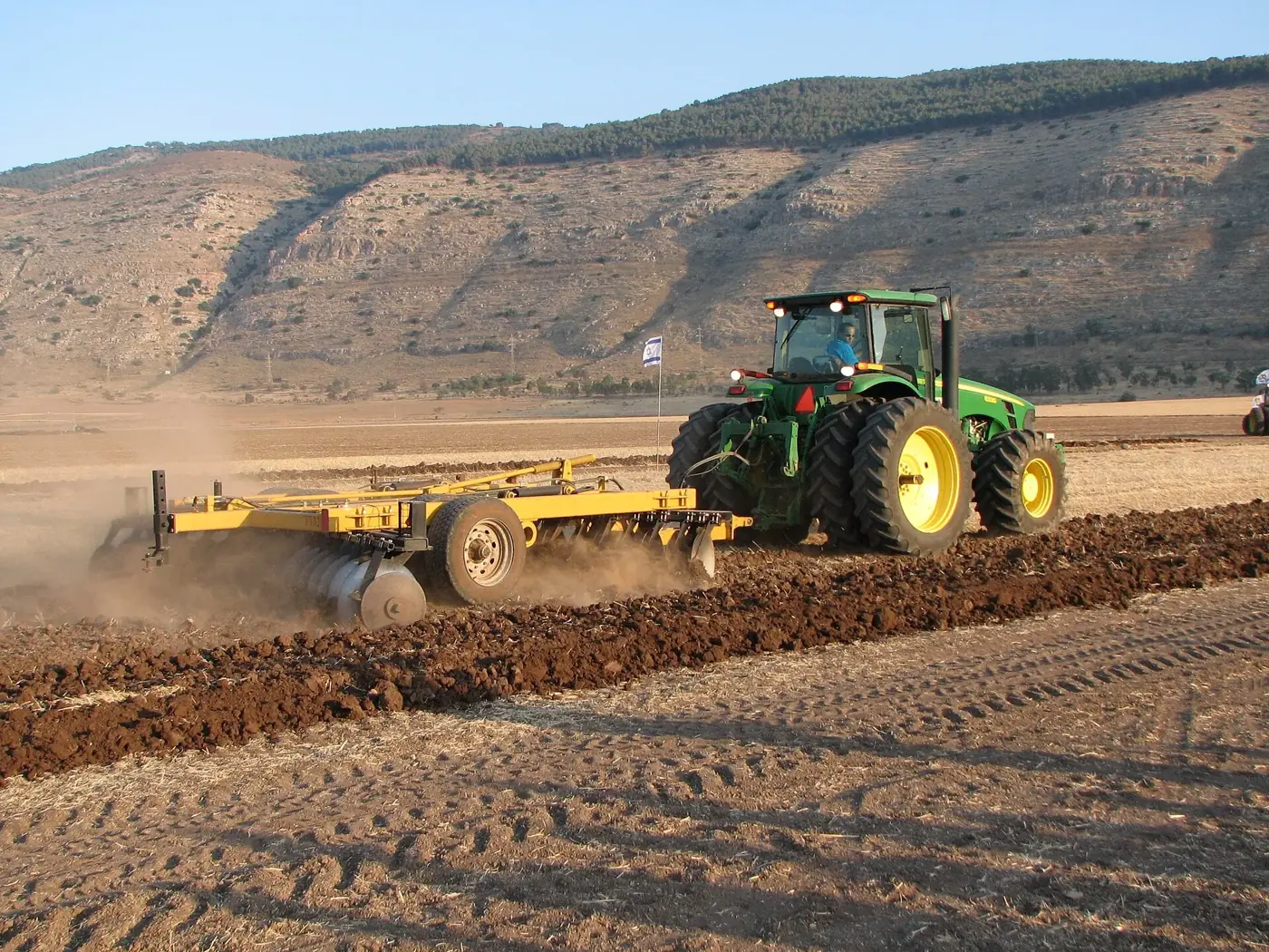 Trator com grade niveladora preparando solo para plantio de soja e milho